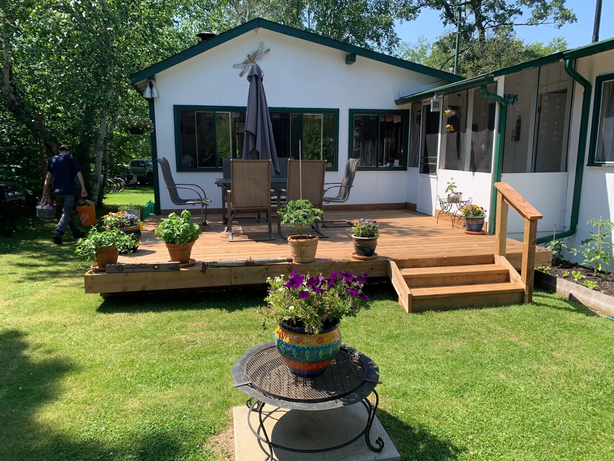 Finished deck with box stairs and a handrail behind a white cottage with green trim